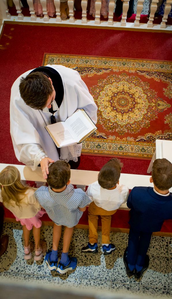 Pastor u oltáře žehná mladým členům sboru